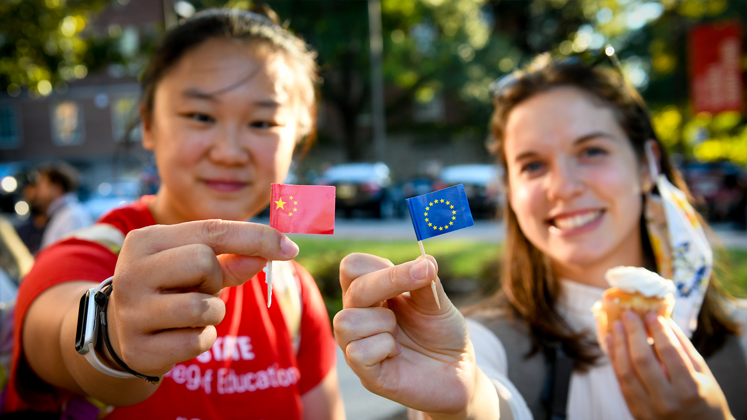 Two students holding up two flags (one Chinese and one European)