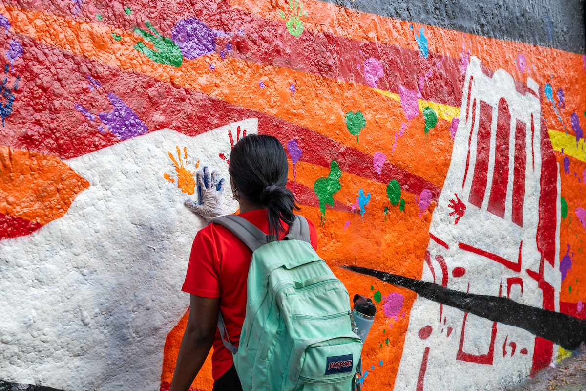 Student places handprint on a mural.