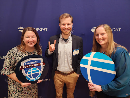 An image of Kyle Miskell, Courtney Hughes, and Kristen Hetrick at the University Fellowships Office holding the Fulbright logo and giving Wolfies.