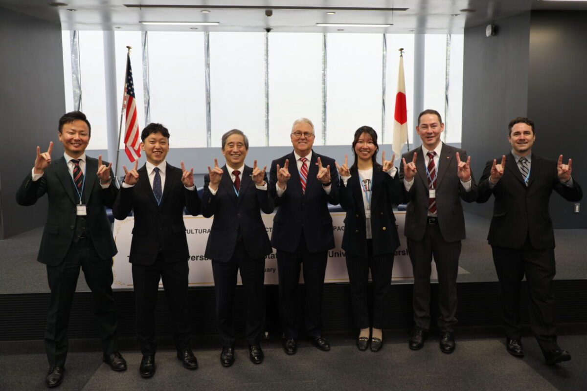 NC State Chancellor Randy Woodson and Nagoya University President Naoshi Sugiyama pose with colleagues while showing their Wolfies.