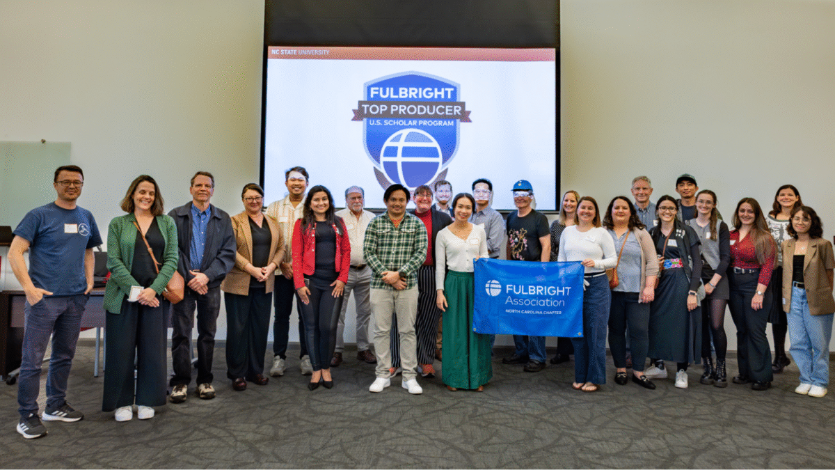 Fulbright Week attendees gathered in front of a Fulbright Week presentation screen