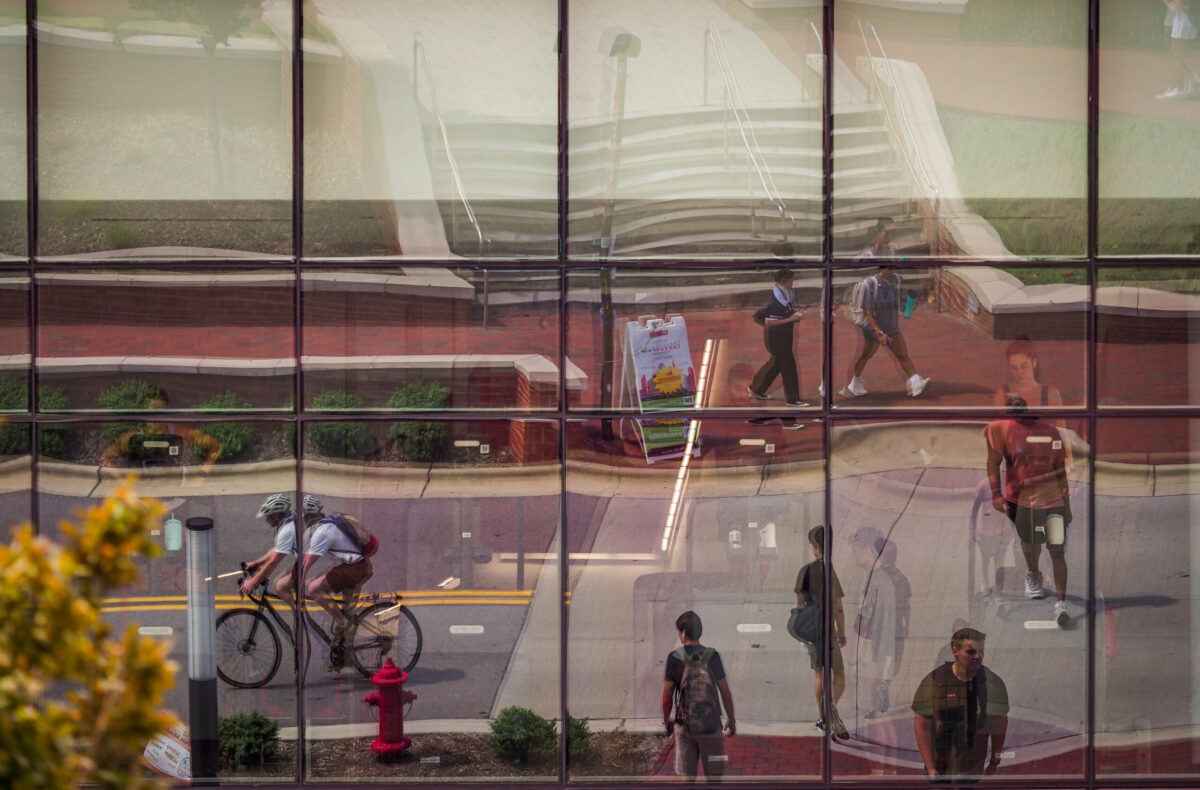 Students make their way inside and around Talley Student Union on the first day of classes. Image shows their reflections outside the building