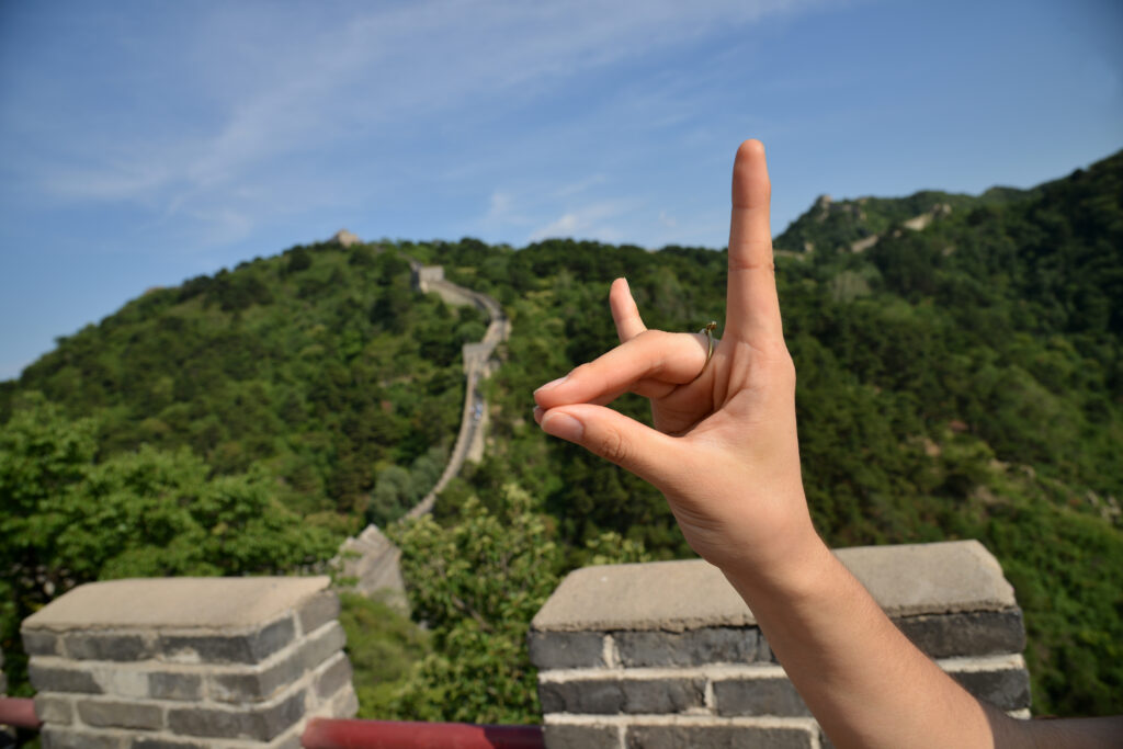 A hand in the wolfies symbol in front of the Great Wall of China