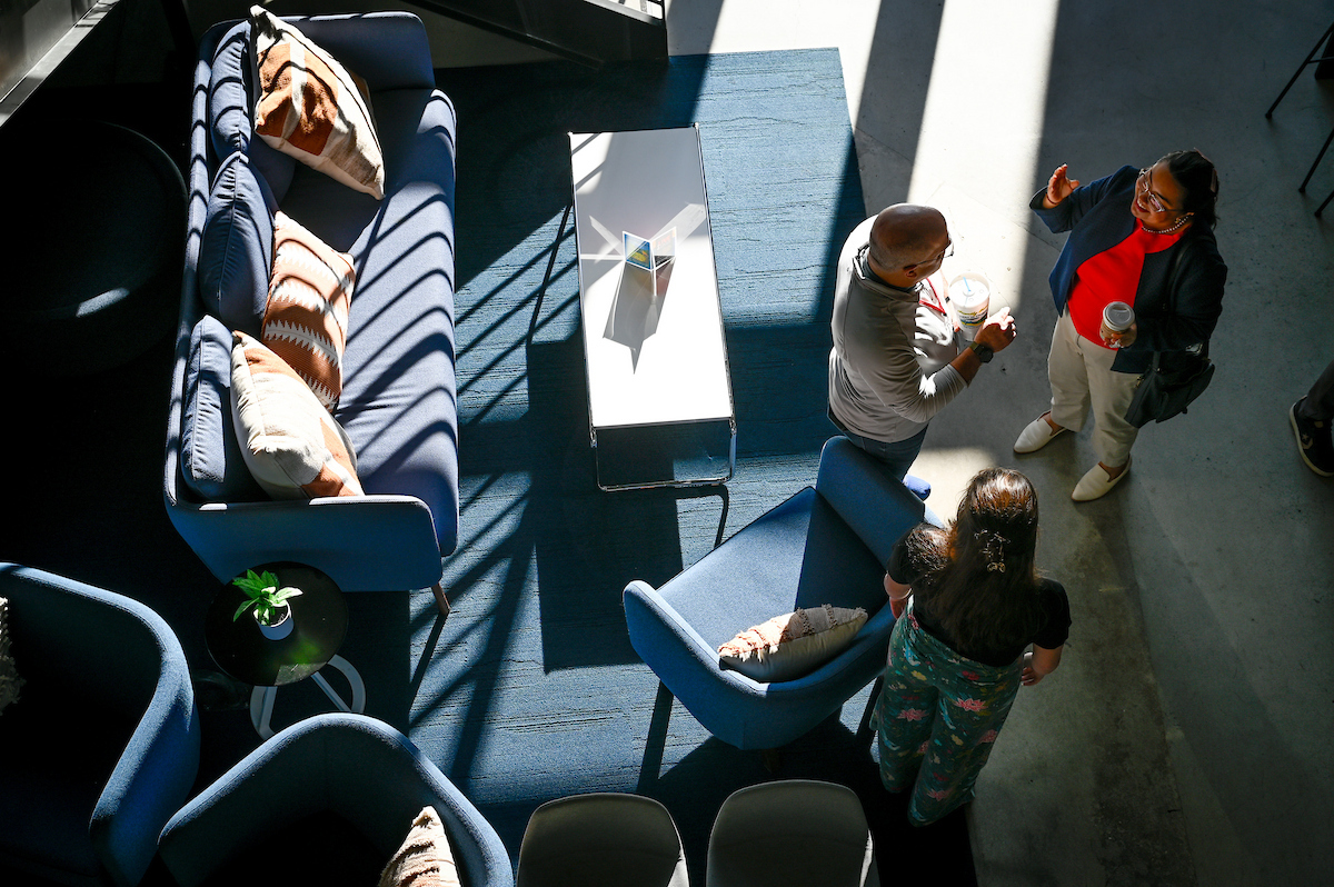 A group of faculty conversing at a committee meeting with the sunlight coming in through the window.
