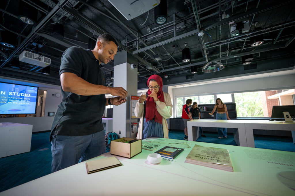 An image of two students reviewing archival material in a design studio. 