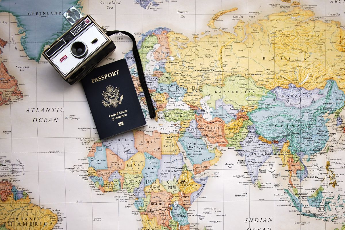 A global map with a camera and a passport laid out on top of it.