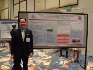 Brian Waters standing in front of a research poster during a research symposium.