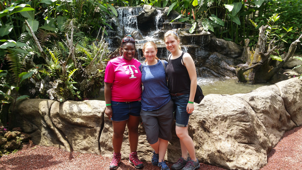 Three women taking a group photo during a hike in a forest in Costa Rica.