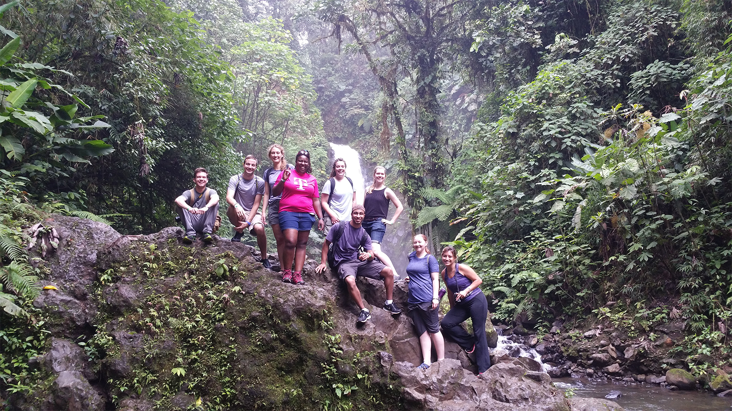 A group of students taking a group photo while on a hike in a forest in Costa Rica.